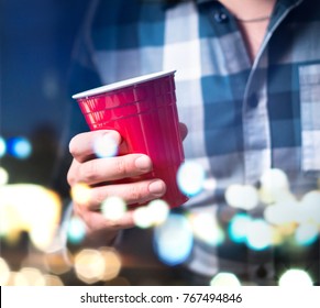 Young Man Holding Red Cup In A Luxury Party. Person Having Fun And Drinking Alcohol. Abstract And Modern Celebration Concept.