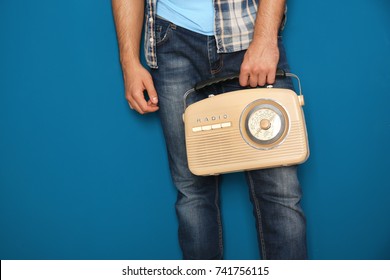 Young Man Holding Retro Radio On Color Background