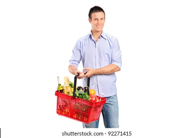 Young Man Holding A Shopping Basket Full With Products Isolated Against White Background