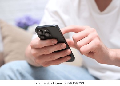A young man is holding smartphone and looking at screen. High quality photo