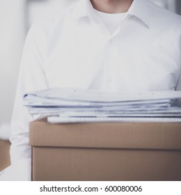 Young Man holding a stack of cardboard boxes standing in office