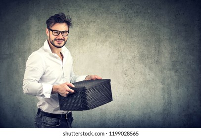 Young man holding stuff box being in job search while smiling at camera