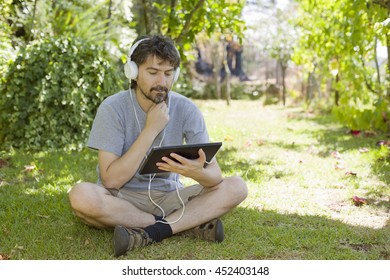 young man holding a tablet with headphones, outdoor - Shutterstock ID 452403148