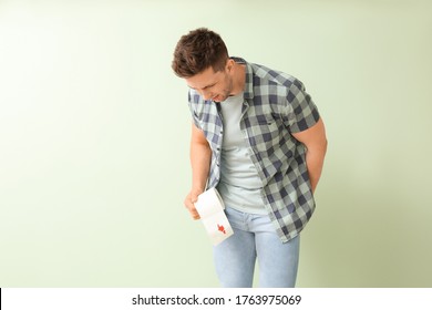 Young man holding toilet paper with blood spot on color background. Hemorrhoids concept