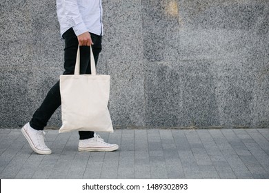 Young man holding white textile eco bag against urban city background. . Ecology or environment protection concept. White eco bag for mock up. - Shutterstock ID 1489302893