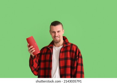 Young Man Holding Wireless Portable Speaker On Green Background