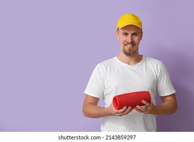 Young Man Holding Wireless Portable Speaker On Violet Background