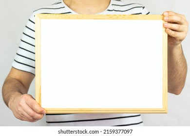 Young Man Holding Wooden Frame With Blank Area, Copy Space, Isolated On White Background, Paper Area For Text On Wooden Pinboard, Banner Idea, Message Text Concept