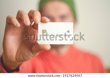 A young man holds a blank bank credit card. Cashless payments, banks, loans and online payment concept.