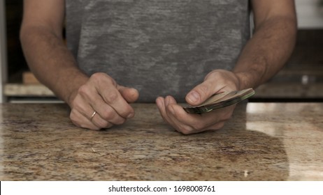 A Young Man Holds Money In His Hands. A Guy Counts The Canadian Dollars That He Took Out Of The Envelope. A Young Husband Recounts A Large Amount Of Money. Counting Money In A Kitchen Payday