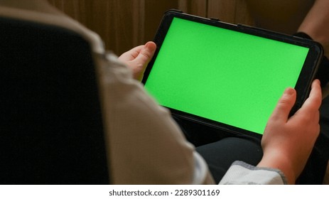 a young man holds a tablet with a green screen. close-up. home furnishings. Chroma key. View over shoulder. - Powered by Shutterstock