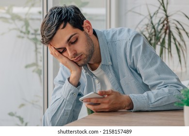young man at home bored looking at mobile phone