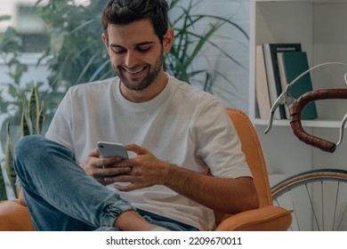 young man at home on sofa with mobile phone - Shutterstock ID 2209670011