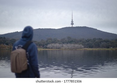 A Young Man In A Hoodie, Looking Out Over Lake Burley Griffin Towards Black Mountain And Telstra Tower In Canberra.