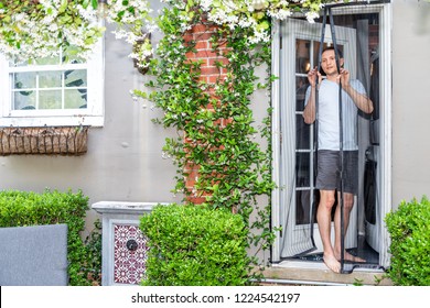 Young man, house, entering exiting outdoor spring garden with plant flowers covering brick wall in backyard porch of home by door, insect mosquito pest net