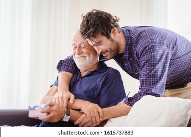 young man hugs the uncle old man warmly inside the house, son happy and love his father or grand father with gift box concept