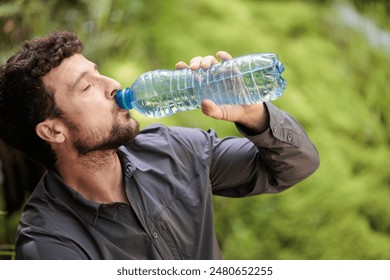 Young man hydrating himself drinking water sitting pure nature while taking a route in nature feeling free, paradisiacal place - Powered by Shutterstock