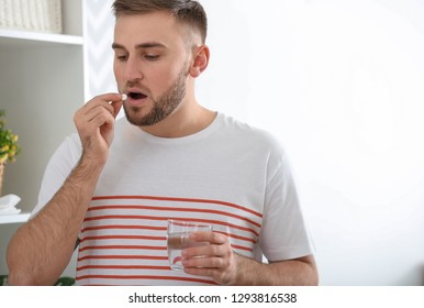 Young Man Ill With Flu Taking Medicine At Home