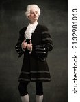 Young man in image of Amadeus Mozart, medieval person isolated on dark vintage background. Retro style, comparison of eras concept. Elegant male model as historical character, great music compose