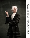 Young man in image of Amadeus Mozart, medieval person isolated on dark vintage background. Retro style, comparison of eras concept. Elegant male model as historical character, great music compose