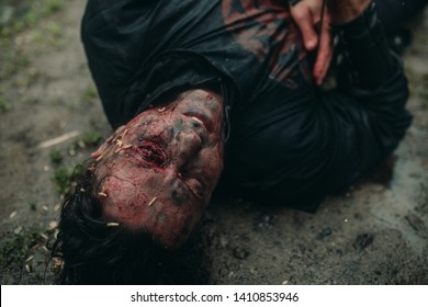 A Young Man In The Image Of A Murdered Medieval Knight Lying On The Ground And With Worms Crawling On His Face. Top View.