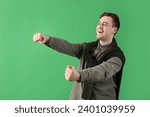 Young man with imaginary steering wheel on green background