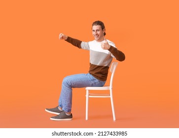 Young Man With Imaginary Steering Wheel Showing Thumb-up On Color Background