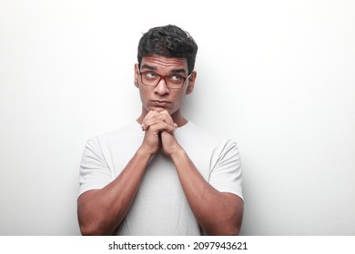 Young man of Indian ethnicity looking up with a doubtful  face