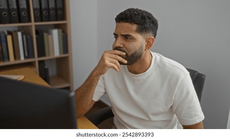 Young man indoors focused at a desk in an office setting - Powered by Shutterstock