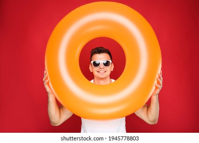 Young Man With Inflatable Ring On Red Background