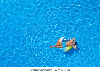 Young Man With Inflatable Ring In Swimming Pool, Top View. Space For Text