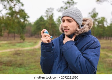 Young Man With Inhaler Having Asthma Attack Outdoors