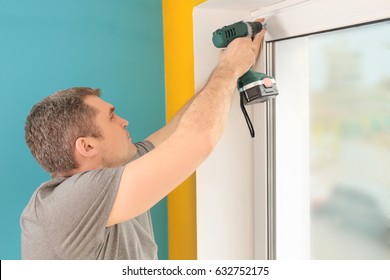 Young Man Installing Window Shades At Home