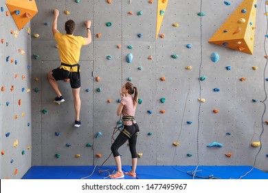 Young man with instructor climbing wall in gym - Powered by Shutterstock