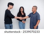 A young man introduces himself to the father of his girlfriend, who watches on. Shaking hands in a cordial fashion. Isolated on a white background.