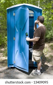 A Young Man Investigating A Blue Porta Potty Located On The Hiking Trail.  Desperate Times Call For Desperate Measures.