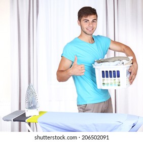 Young Man Ironing Clothes In Room