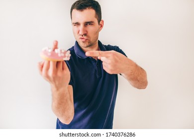 Young Man Isolated Over White Background. Rude Guy Hold Donut On One Finger And Show Sign. Two Fingers Together On Another Hand.