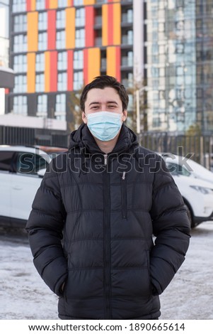 a young man in a jacket wearing a protective medical mask on his face. protective mask on the face of the virus and contamination