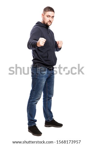 A young man in jeans in a fighting stance. Full height. Isolated on a white background. Vertical.