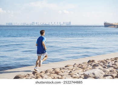 A Young Man Jogging Along a Waterfront Path on a Bright Sunny Day With City Skyline in the Distance - Powered by Shutterstock