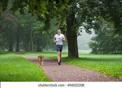 Young Man Jogging With His Dog In Park