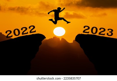 A young man jump between 2022 and 2023 years over the sun and through on the gap of hill silhouette evening colorful sky. happy new year 2023.	 - Shutterstock ID 2235835707