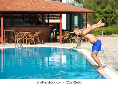 Young Man Jumping In Swimming Pool At Resort