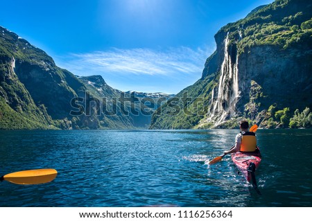 young man kayaking along the fjord geiranger enjoying the waterfall 