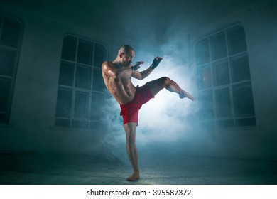 The Young Man Kickboxing In Blue Smoke