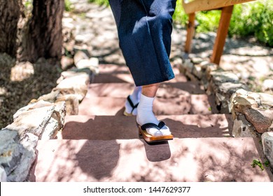 Young Man In Kimono Costume Walking In Geta Tabi Socks Shoes Up Stone Steps In Outdoor Garden In Japan