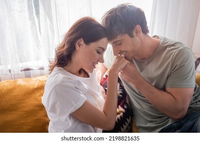 Young man kissing hand of brunette girlfriend on bed in camper van