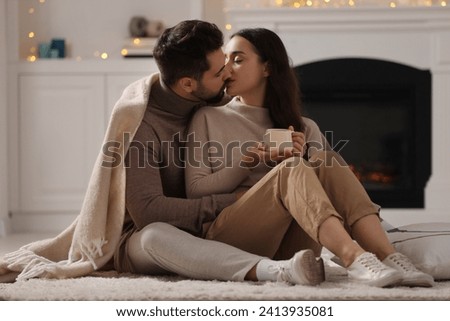 Young man kissing his girlfriend on soft carpet at home