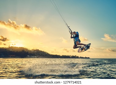                      Young man kite boarder jumps over the sea at sunset           